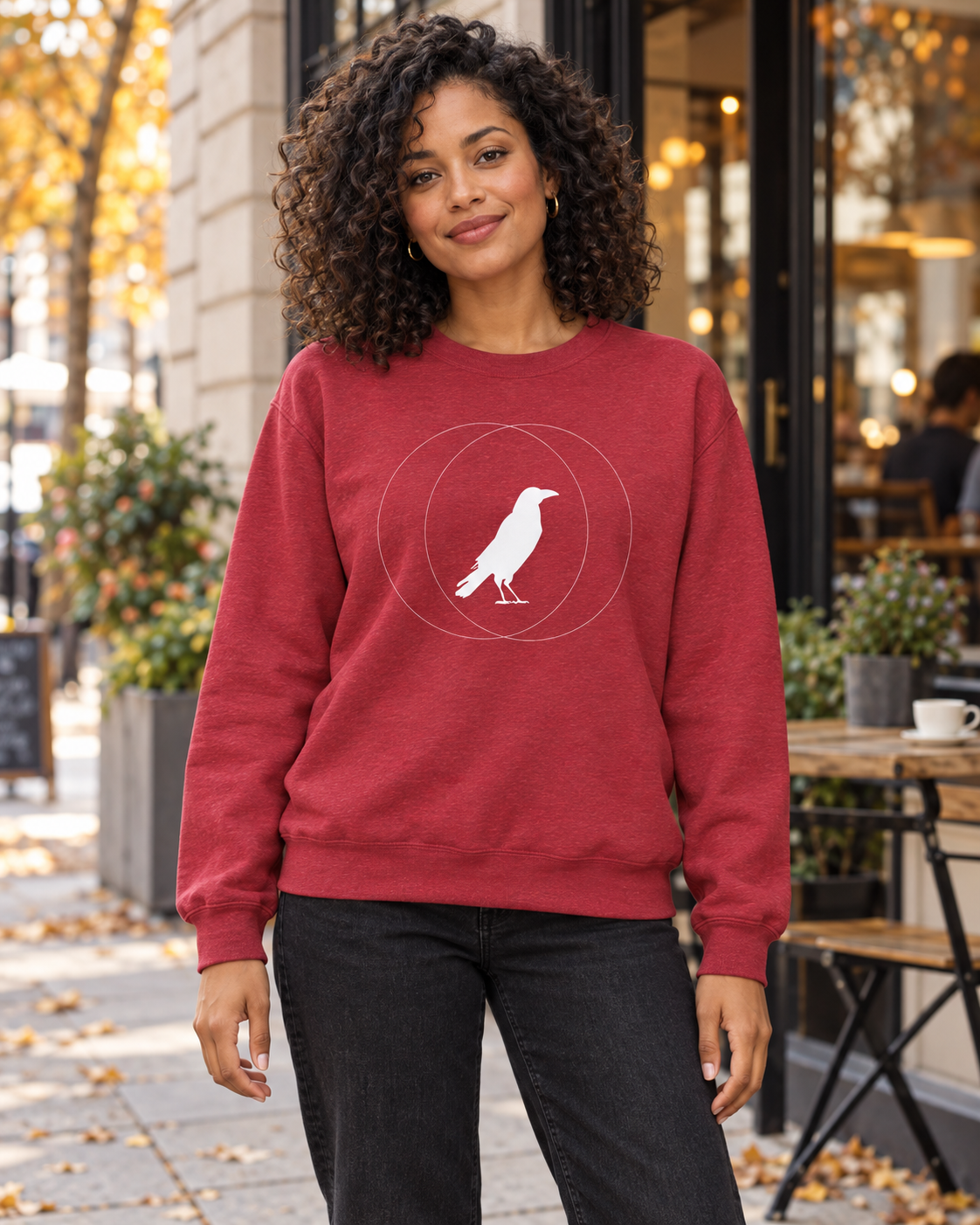 Woman wearing a red Wise Crow sweatshirt outside a cafe