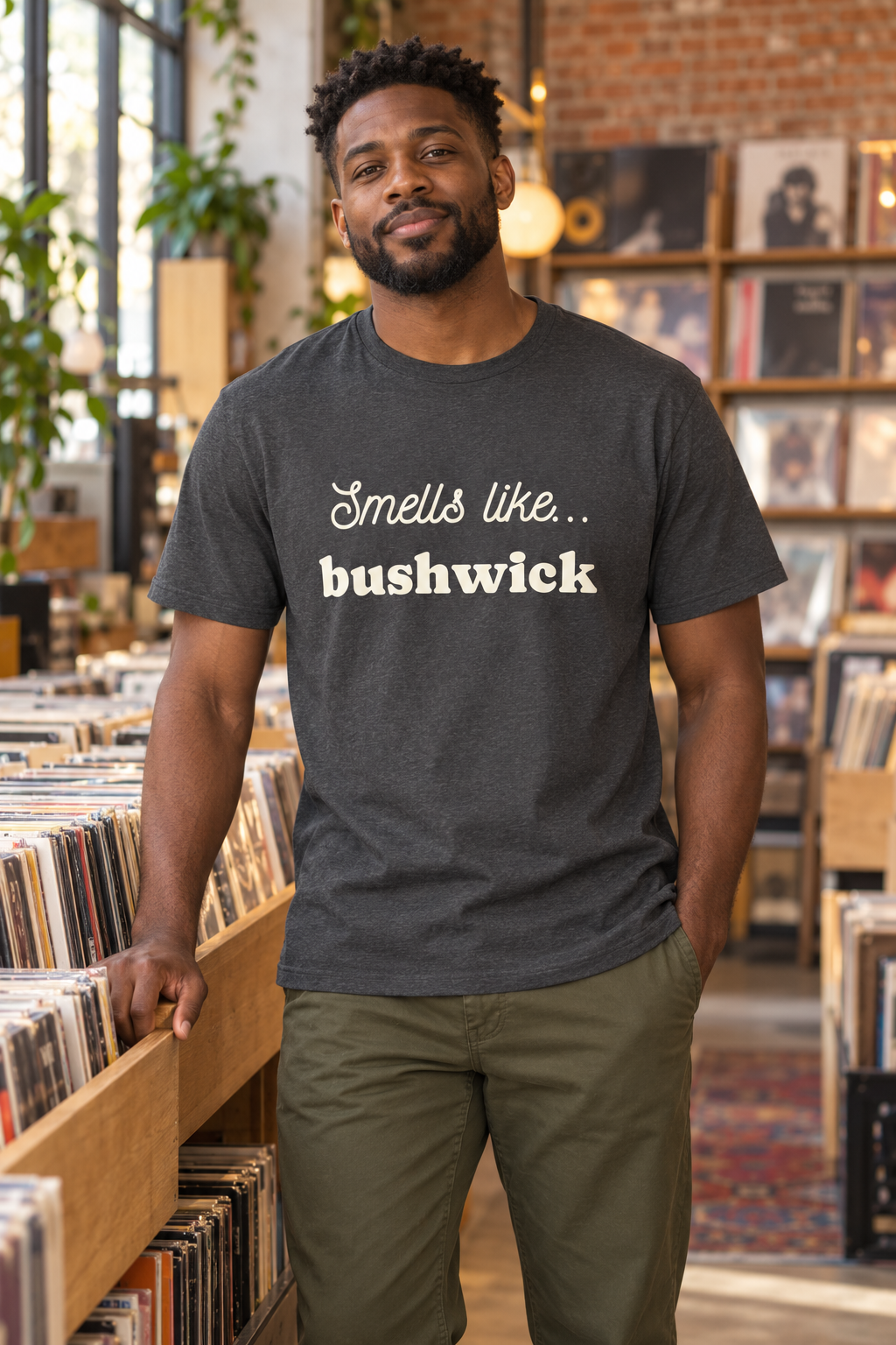 Man wearing a charcoal Smells Like Bushwick shirt in a record shop