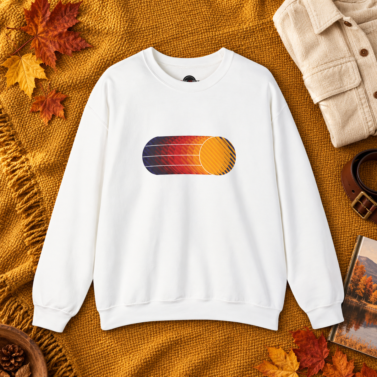 White Retro Sunset sweatshirt laid flat with autumn leaves