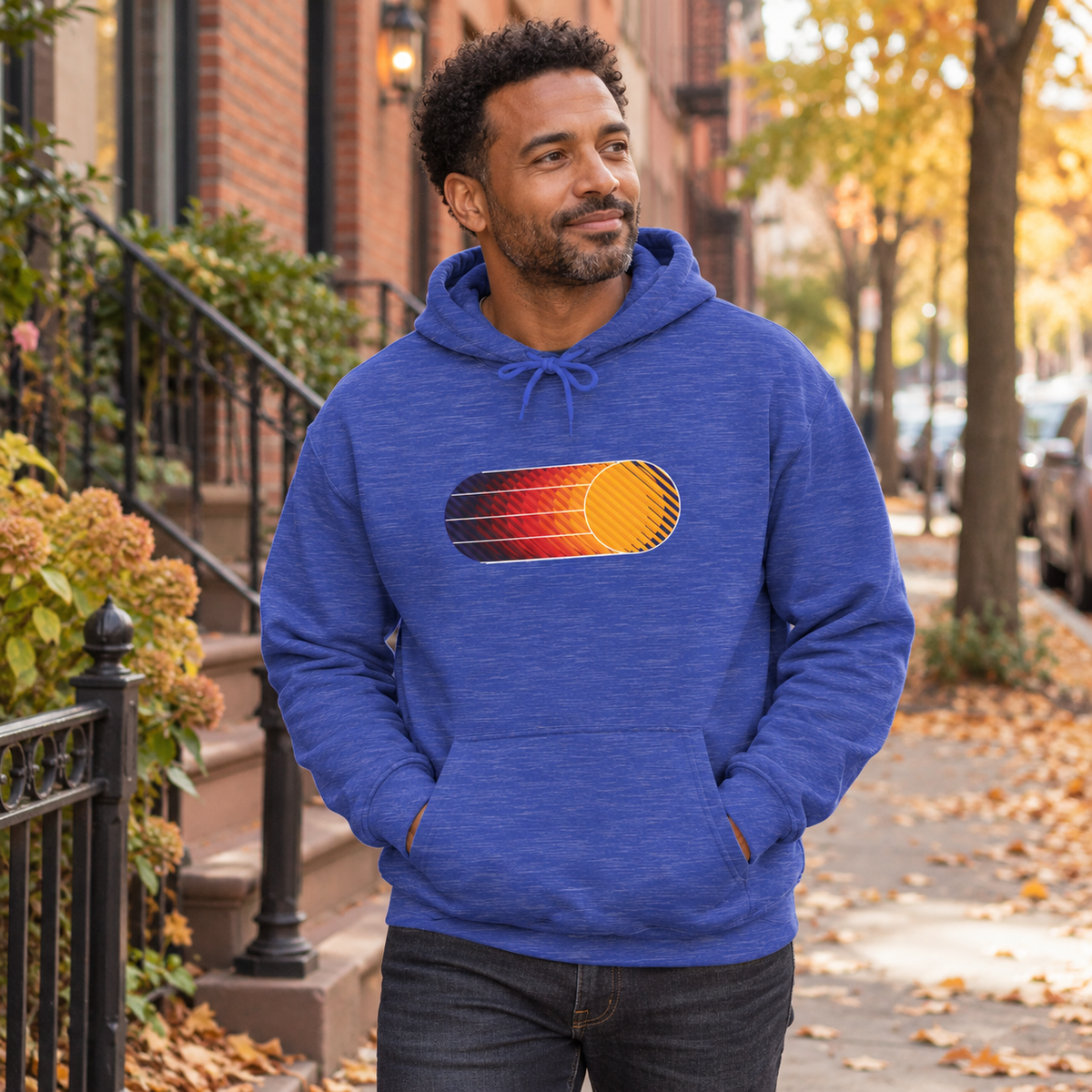 Male model wearing a Heather Sport Royal Retro Sunset graphic hoodie in New York during fall