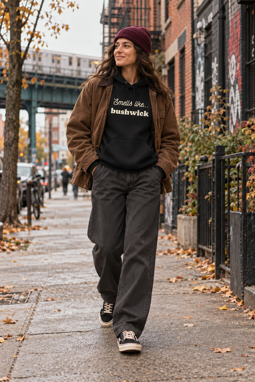 Woman wearing a black Smells Like Bushwick hoodie on a sidewalk