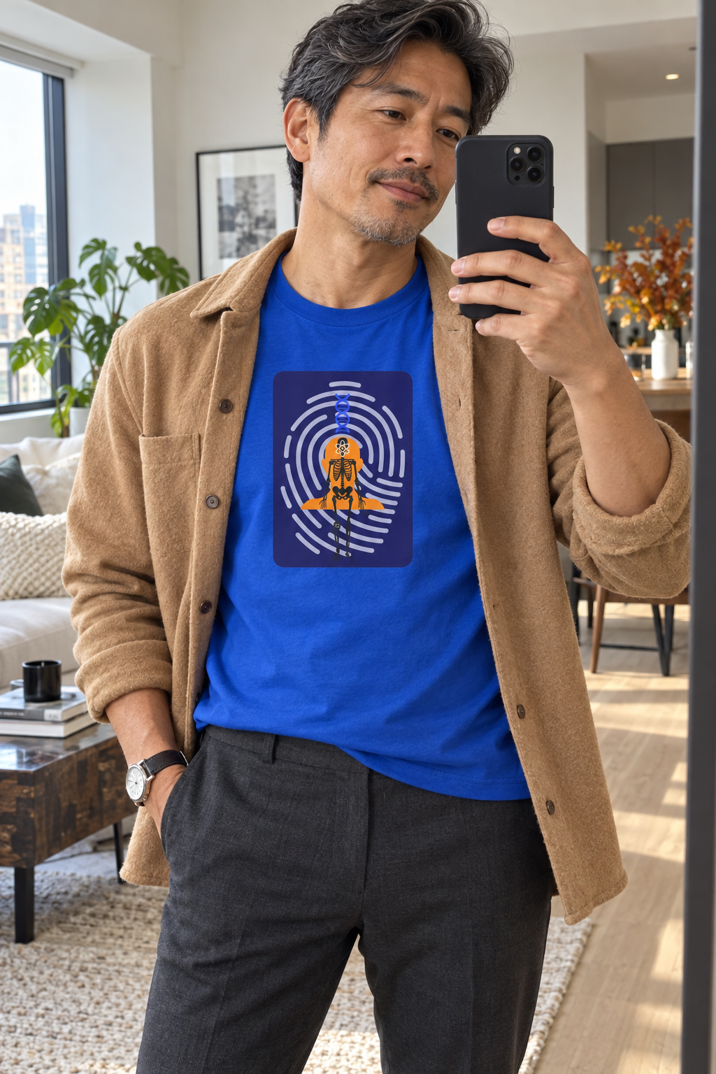 Man wearing a blue Human Blueprint shirt and tan jacket in a mirror
